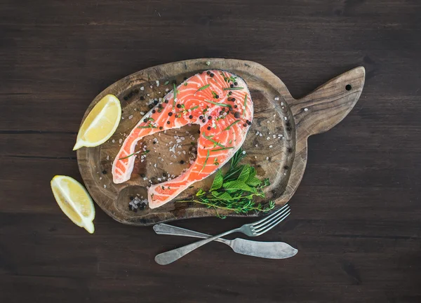 Raw salmon steak with fresh herbs, lemon and spices on rustic wo — Stock Photo, Image