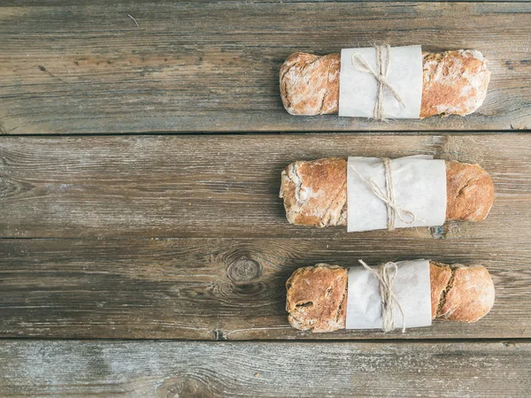 Pan de pueblo rústico recién horneado (baguette) sobre madera rugosa — Foto de Stock