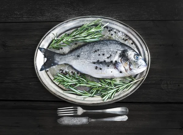 Pesce di mare fresco (orata) su un piatto di metallo con rosmarino e spi — Foto Stock