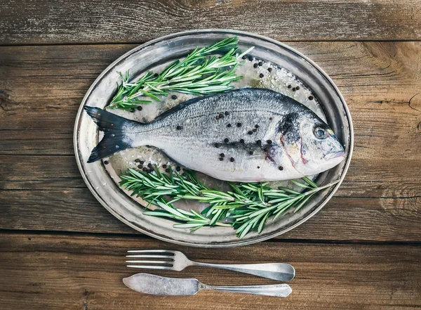 Свежая морская рыба (морской лещ) на металлической тарелке с розмарином и спи — стоковое фото