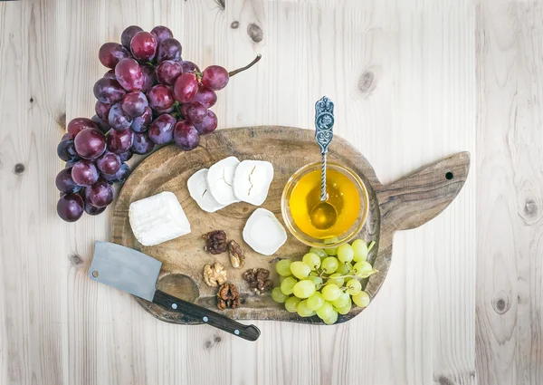 Queso brie de cabra con uvas frescas y miel en una madera rústica — Foto de Stock