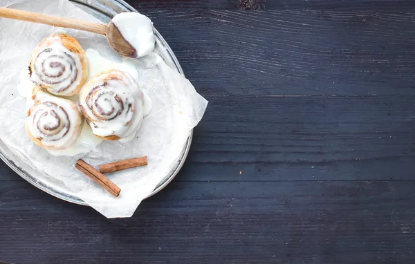 Rollos de canela con glaseado de queso crema y palitos de canela en un —  Fotos de Stock