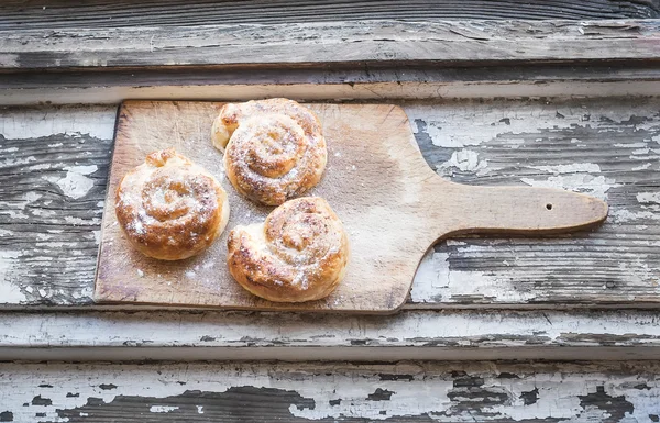 Zimtbrötchen auf einem rustikalen Holzbrett — Stockfoto