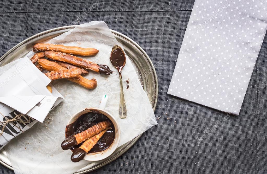 Churros with chocolate sauce on a metal plate