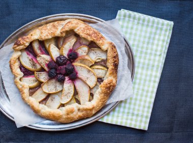 Elma ve berry Galette'ye bir karanlık masa örtüsü üzerinde metal bir tabak üzerinde