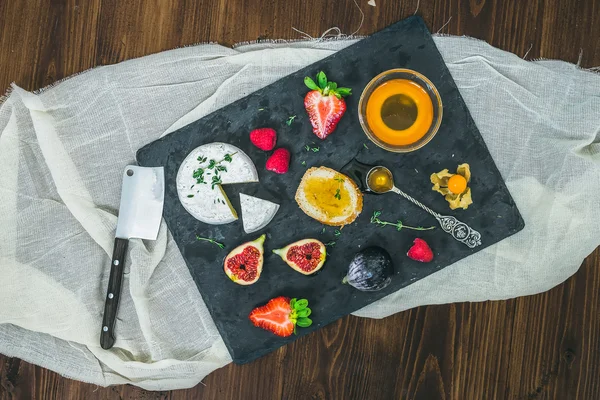 Cheese and fruit set on a dark stone board — Stock Photo, Image