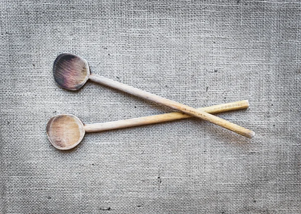 Two rustic wood cooking spoons over a sackcloth surface — Stock Photo, Image