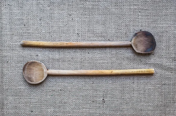 Dos cucharas rústicas para cocinar de madera sobre una superficie de saco — Foto de Stock