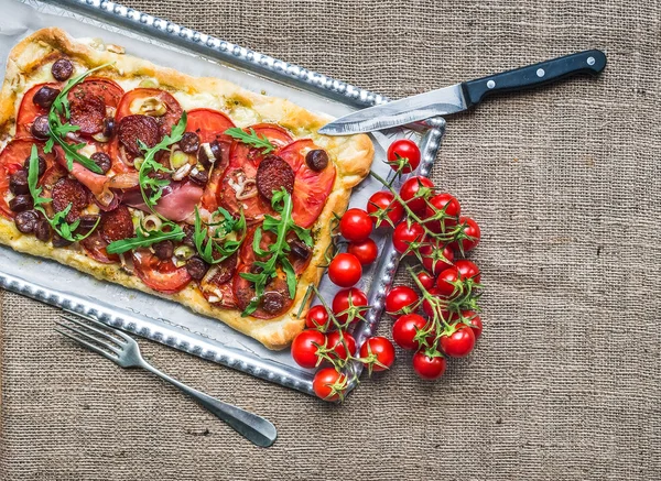 Hemgjorda fyrkantiga pizza med kött, salami, körsbärstomater och fre — Stockfoto