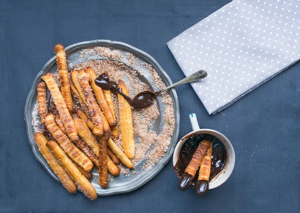 Churros with chocolate sauce on a metal plate over a linen backg — Stock Photo, Image