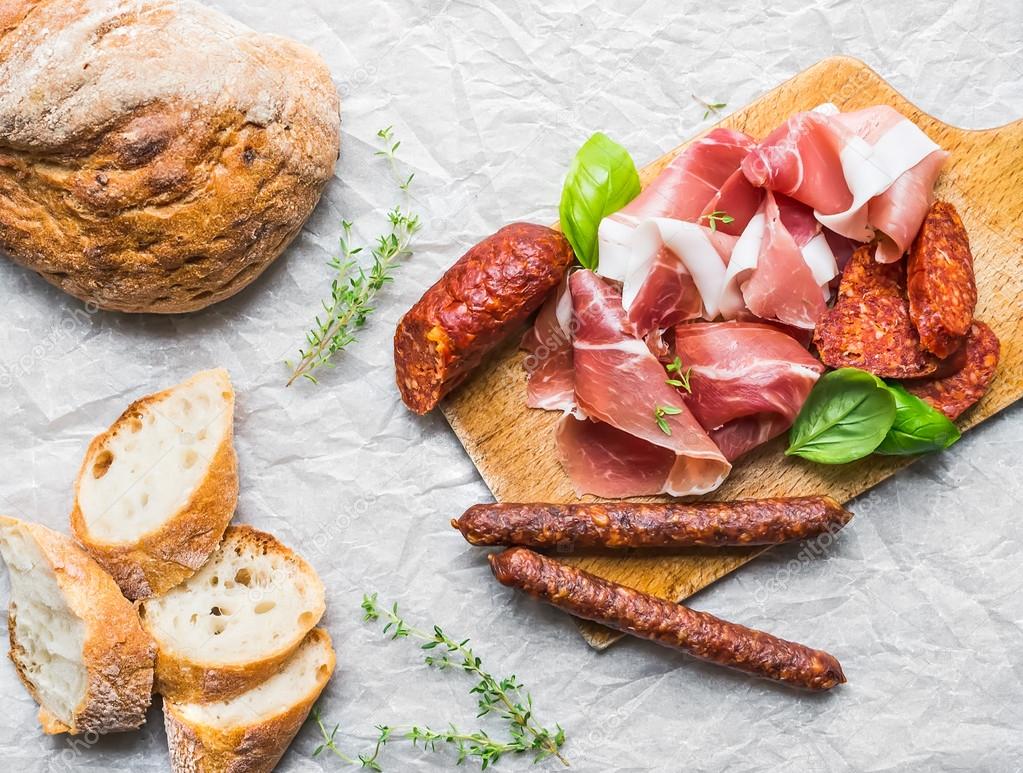 Meat appetizers selection, a loaf of rustic village bread and ba