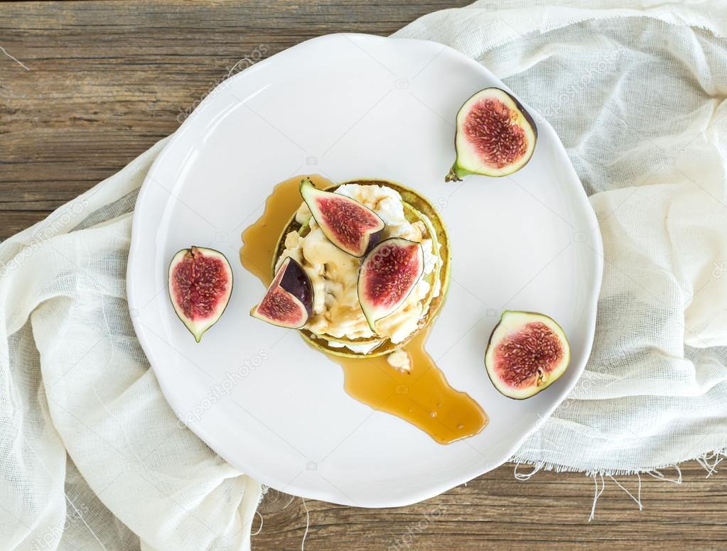 Marrow pancakes with fresh figs, honey and goat cheese on a whit