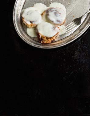Tarçın krem krema ve şeker tozu ile metal bir tabak üzerinde rulo.