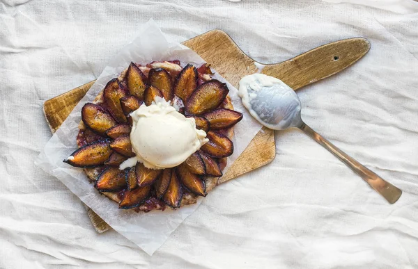 Plum pie with vanilla ice-cream ball on a wooden board — Stock Photo, Image