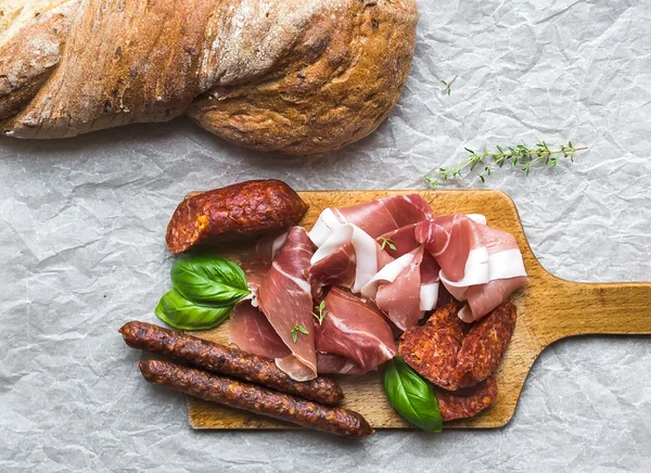 Meat plate on rustic wood board over a rough sackcloth backgroun — Stock Photo, Image