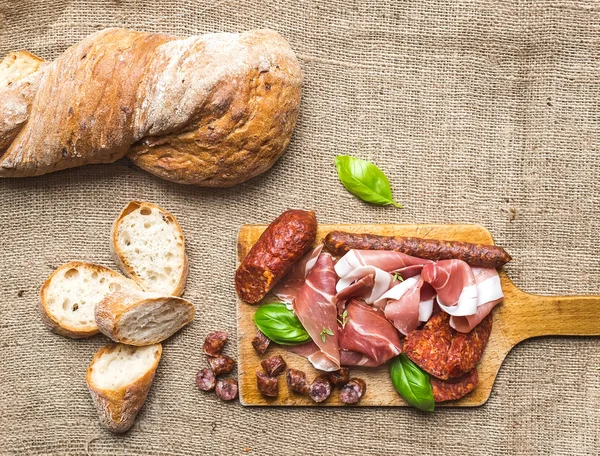 Selección de aperitivos de carne y una barra de pan rústico del pueblo en — Foto de Stock