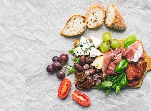 Meat and cheese plate on rustic wood board over a white paper ba — Stock Photo, Image