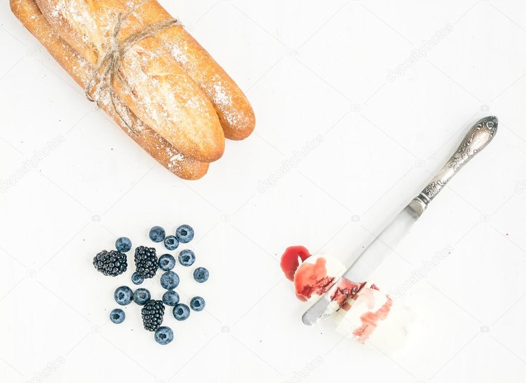 Freshly baked baguettes, berries and a piece of goat cheese