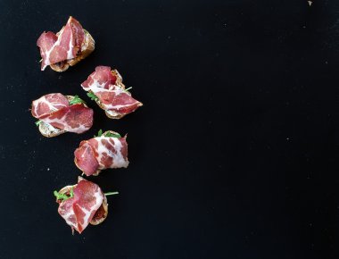 Bruschettas kurutulmuş domates, roka ve füme etin üzerine bir 