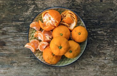 Bir kaba ahşap arka plan üzerinde olgunlaşmış taze sulu mandalina tabak