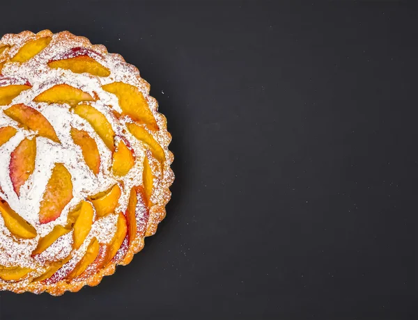 Peach pie with sugar powder on dark with a space for your iscrip