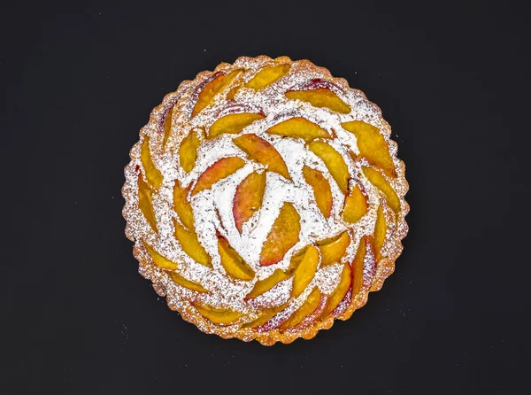 Peach pie met suiker poeder op donker — Stockfoto