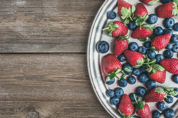 Fresh strawberry and blueberry mix on a metal dish (tray) over a — Stock Photo, Image