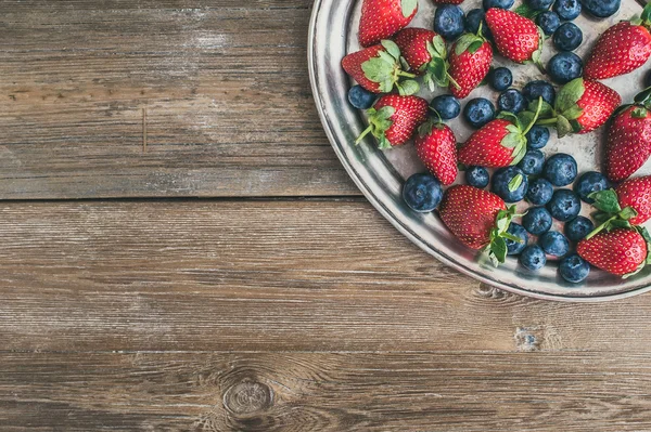 Fresh strawberry and blueberry mix on a metal dish (tray) over a — Stock Photo, Image