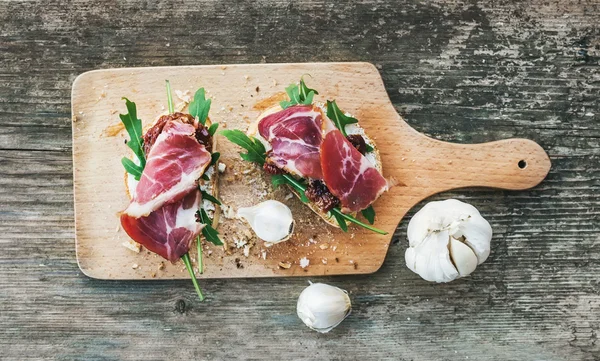 Brushetta set with smoked meat, arugula, garlic and dried tomato — Stock Photo, Image