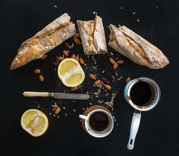 Rustic breakfast set of french baguette broken into pieces, grapefruit, sunflower seeds, almonds and coffee on dark — Stock Photo, Image