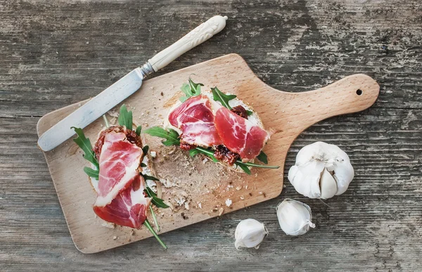 훈제 고기, arugula, 마늘, 말린된 토마토와 Brushetta 설정 — 스톡 사진