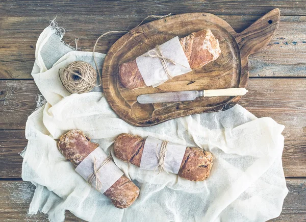 Pan de pueblo rústico recién horneado (baguettes) envuelto en papel — Foto de Stock