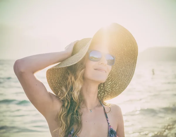 Menina loira jovem em óculos de sol e chapéu de palha na praia — Fotografia de Stock