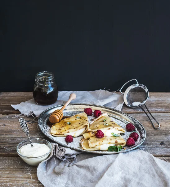 Thin pancakes or crepes with fresh raspberry, cream, mint, on a — Stock Photo, Image