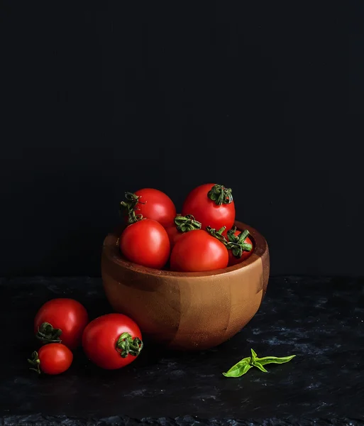 Rijpe kersen-tomaten in houten kom met basilicum, specerijen en zout. — Stockfoto