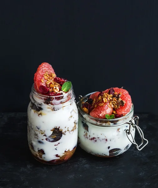 Yogurt y granola de avena con uvas, granada, pomelo en tarro de vidrio alto —  Fotos de Stock