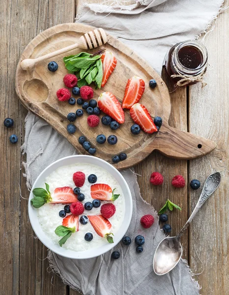 Healthy breakfast set. Rice cereal or porridge with berries and honey over rustic wood backdrop — Stock Photo, Image