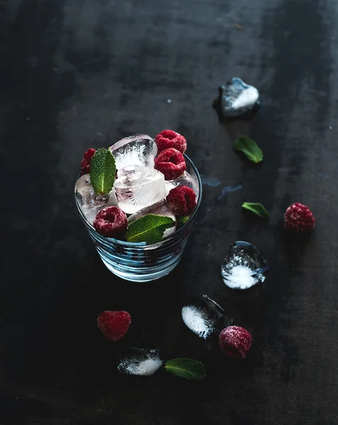 Cubi di ghiaccio con foglie di menta e lampone in vetro su superficie grunge scura — Foto Stock