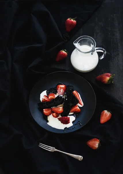 Siyah bisküvi ve siyah zemin üzerinde tatlı krema ile çilekli tatlı — Stok fotoğraf