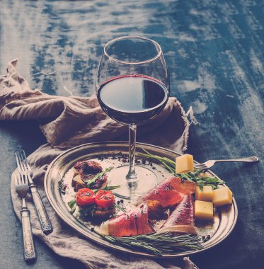 Şarap meze küme. Kırmızı şarap, vintage yemek, brushetta kiraz, kurutulmuş domates, roka, parmesan, bardak füme et gümüş tepsi üzerinde rustik grunge yüzey üzerinde