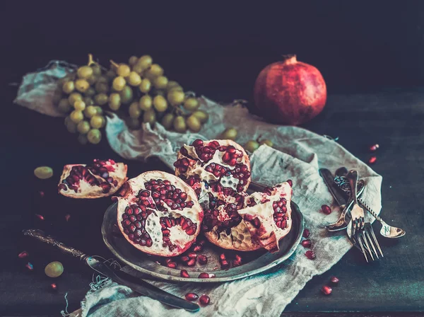 Rustik metal plaka ve bej mutfak havlusu koyu arka plan üzerinde kırmızı olgun soyulmuş nar — Stok fotoğraf
