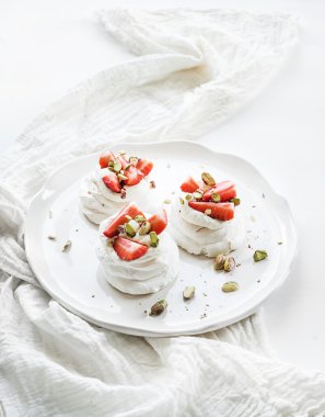 Küçük çilek ve fıstık pavlova beze pasta ile mascarpone krema, beyaz zemin üzerine taze nane