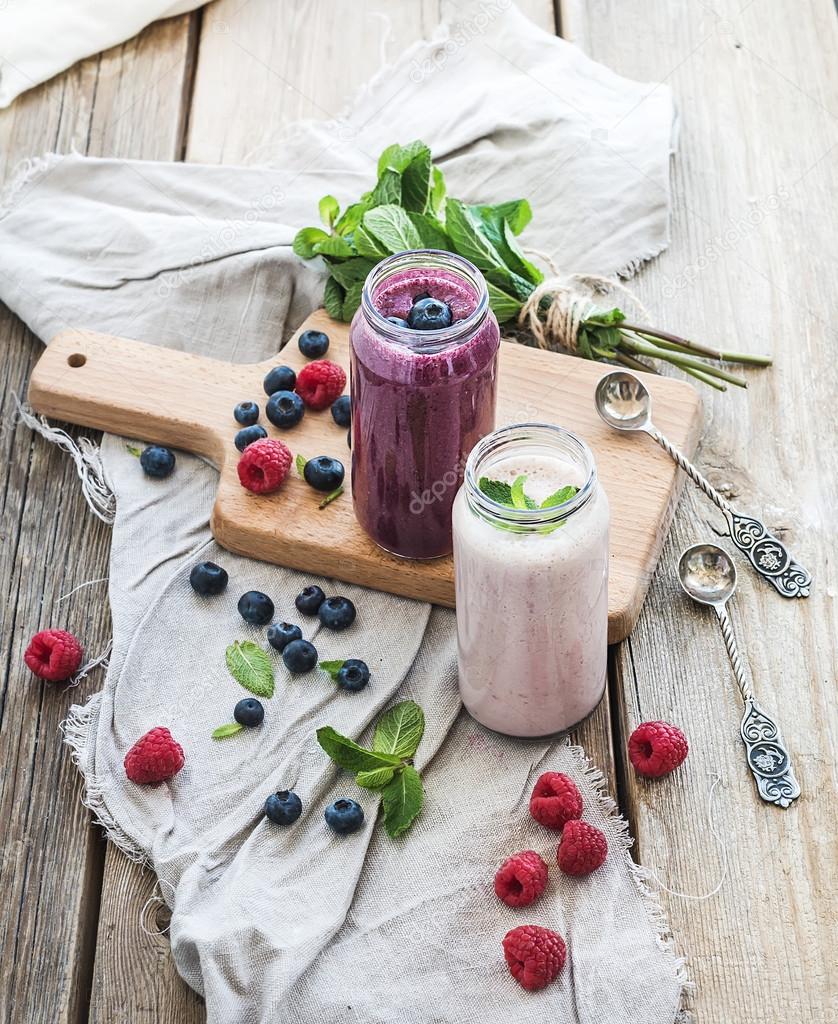 Fresh healthy smoothie with blueberries, raspberries in glass jars and mint