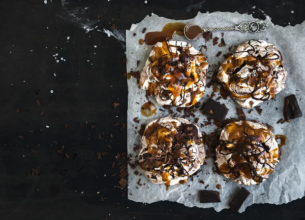 Caramelo salgado e merengues de chocolate sobre superfície grunge escuro, vista superior — Fotografia de Stock