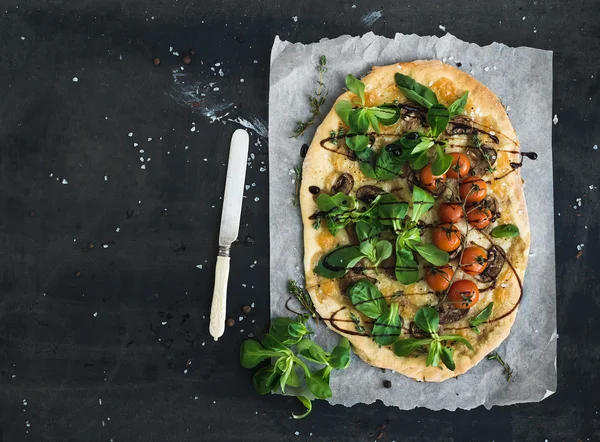 Pizza casera rústica con lechuga fresca de cordero, champiñones y tomates cherry sobre fondo grunge oscuro —  Fotos de Stock