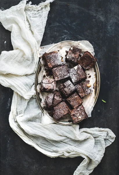 Dark chocolate and walnut brownie squares on a silver tray over black grunge backdrop — Stock Photo, Image
