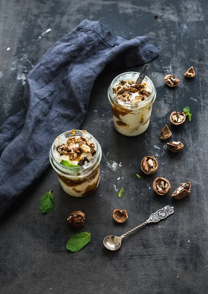 Helado de nuez y caramelo salado en frascos de vidrio con menta fresca sobre una superficie grunge oscura — Foto de Stock