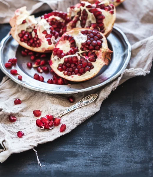 Melograno rosso maturo sbucciato su piastra in metallo rustico e asciugamano da cucina beige su sfondo scuro — Foto Stock