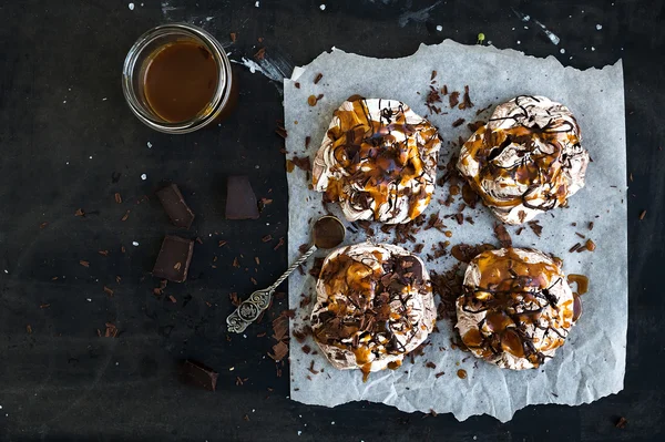 Salted caramel and chocolate meringues over dark grunge surface, top view — Stock Photo, Image