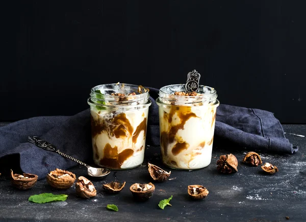 Glace aux noix et caramel salé dans des bocaux en verre avec menthe fraîche sur fond de grunge foncé — Photo